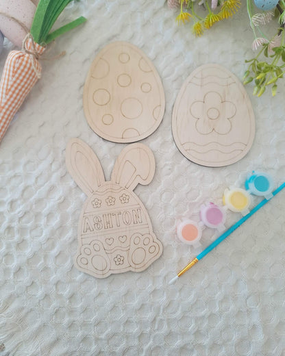 Wooden Easter-themed cutouts with paint and brush on a textured surface