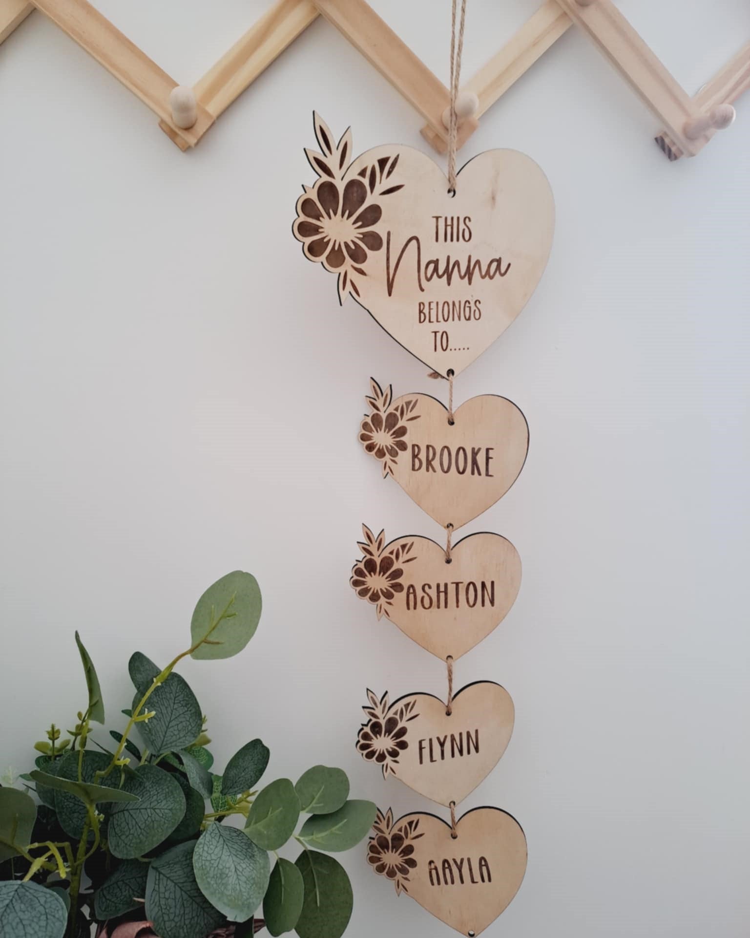 Wooden heart-shaped hanging decoration with engraved names on a light background