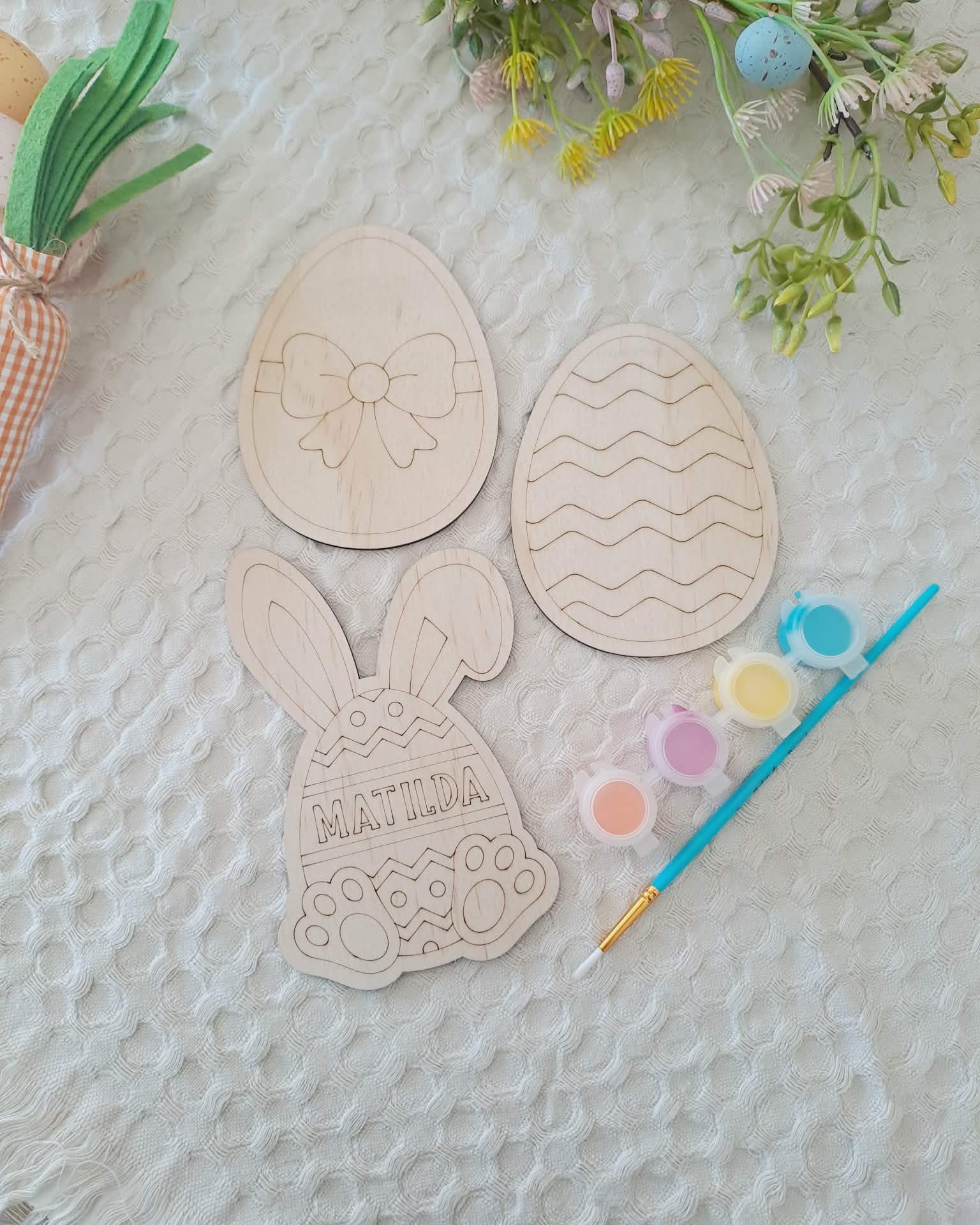 Wooden Easter-themed cutouts with paint and brush on a textured surface